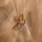 Mixed Metal Link Hoops, featuring gold and silver tones, are beautifully twisted and showcased on sheer beige fabric.