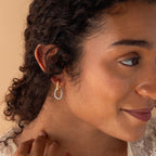 A woman with curly hair wears the Mixed Metal Link Hoops—twisted gold and silver earrings—and smiles slightly.