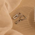 Pave Link Drop Earrings with sparkling CZ diamonds are showcased on a beige fabric backdrop, enhanced by soft lighting for a luxurious effect.