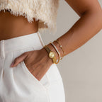 Wearing white pants and a crop top, this person accessorizes with gold bracelets, a watch, and the Princess Diamond Tennis Bracelet while resting a hand casually in their pocket.