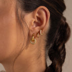 Close-up of a woman’s ear adorned with three bold hoops, including the Duo Pave Link Hoops, with her brown hair styled in a braid.