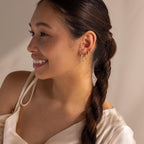 Smiling woman with braided hair wears Inside Out Heart Diamond Hoops and a satin off-shoulder top.