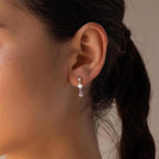 Close-up of a woman's ear wearing the Opal & Diamond Drop Studs, featuring dainty earrings with two crystals and a floral stud design for an elegant look.