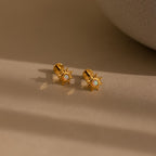 Opal Sun Flat Back Studs feature a central opal stone in a celestial design, resting elegantly on a beige surface under soft lighting. These flat back earrings combine comfort and radiance, perfect for any look.