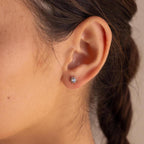 Close-up of a woman’s ear adorned with Opal Sun Flat Back Studs—celestial silver sun-shaped earrings with a central opal. These flat back studs provide comfort and cosmic elegance.