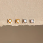Opal Diamond Star Studs—two gold and two silver pairs—displayed on a textured beige surface; perfect for fans of celestial earrings and star jewelry.