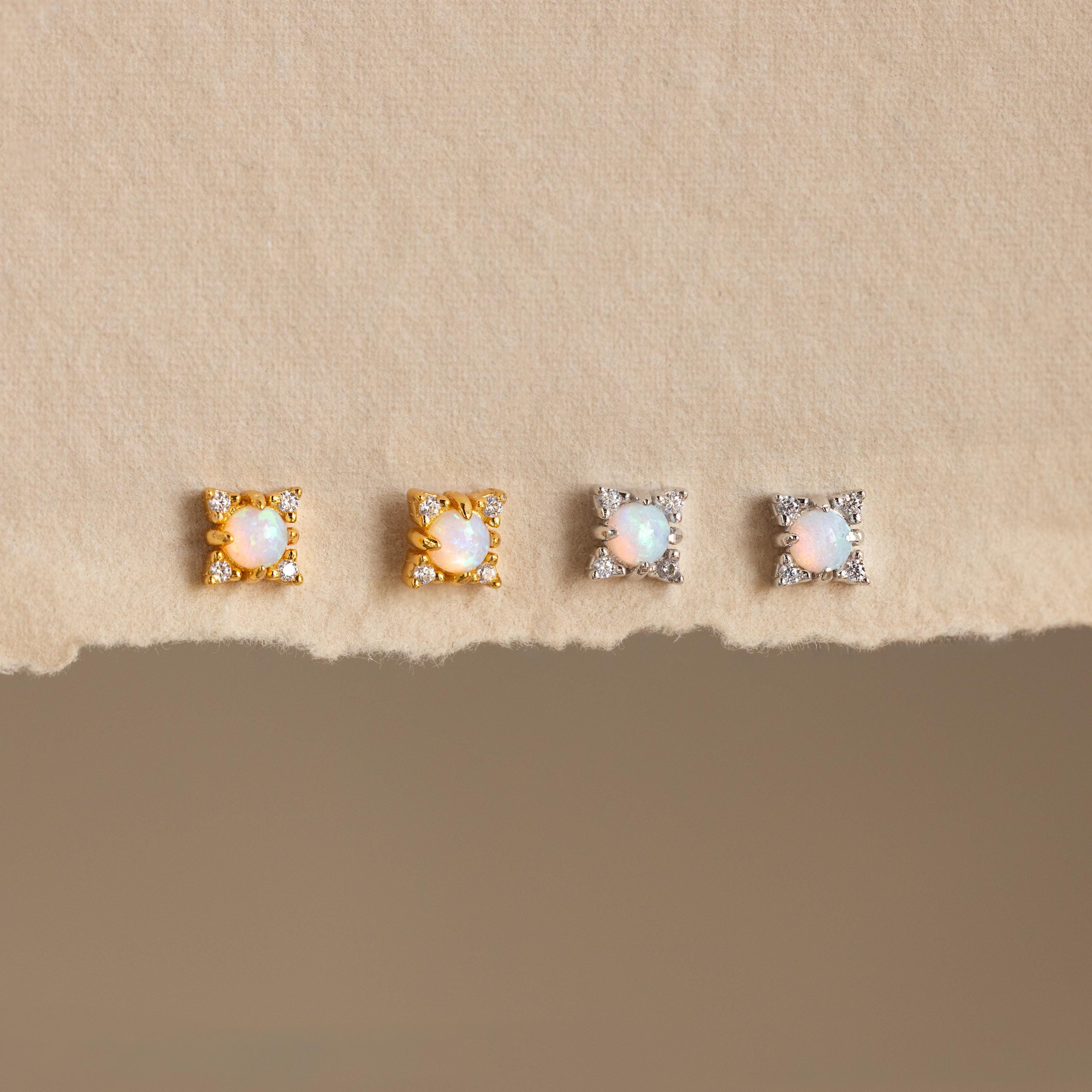 Opal Diamond Star Studs—two gold and two silver pairs—displayed on a textured beige surface; perfect for fans of celestial earrings and star jewelry.