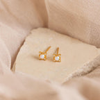 Opal Diamond Star Studs featuring small opals rest on a light beige stone surface, ideal for adding celestial elegance.