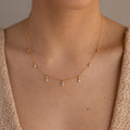 Close-up of a woman wearing the Opal Diamond Station Necklace featuring delicate dangling gemstones—ideal as a unique birthstone gift or elegant bridesmaid keepsake.