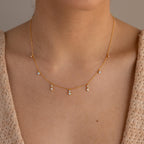 Close-up of a woman wearing the Opal Diamond Station Necklace featuring delicate dangling gemstones—ideal as a unique birthstone gift or elegant bridesmaid keepsake.