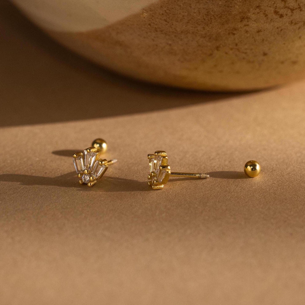 Art Deco Studs with baguette-cut clear stones bring vintage glamour, shown on a beige surface beside a ceramic accent.
