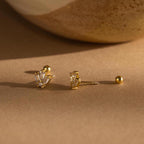 Art Deco Studs with baguette-cut clear stones bring vintage glamour, shown on a beige surface beside a ceramic accent.