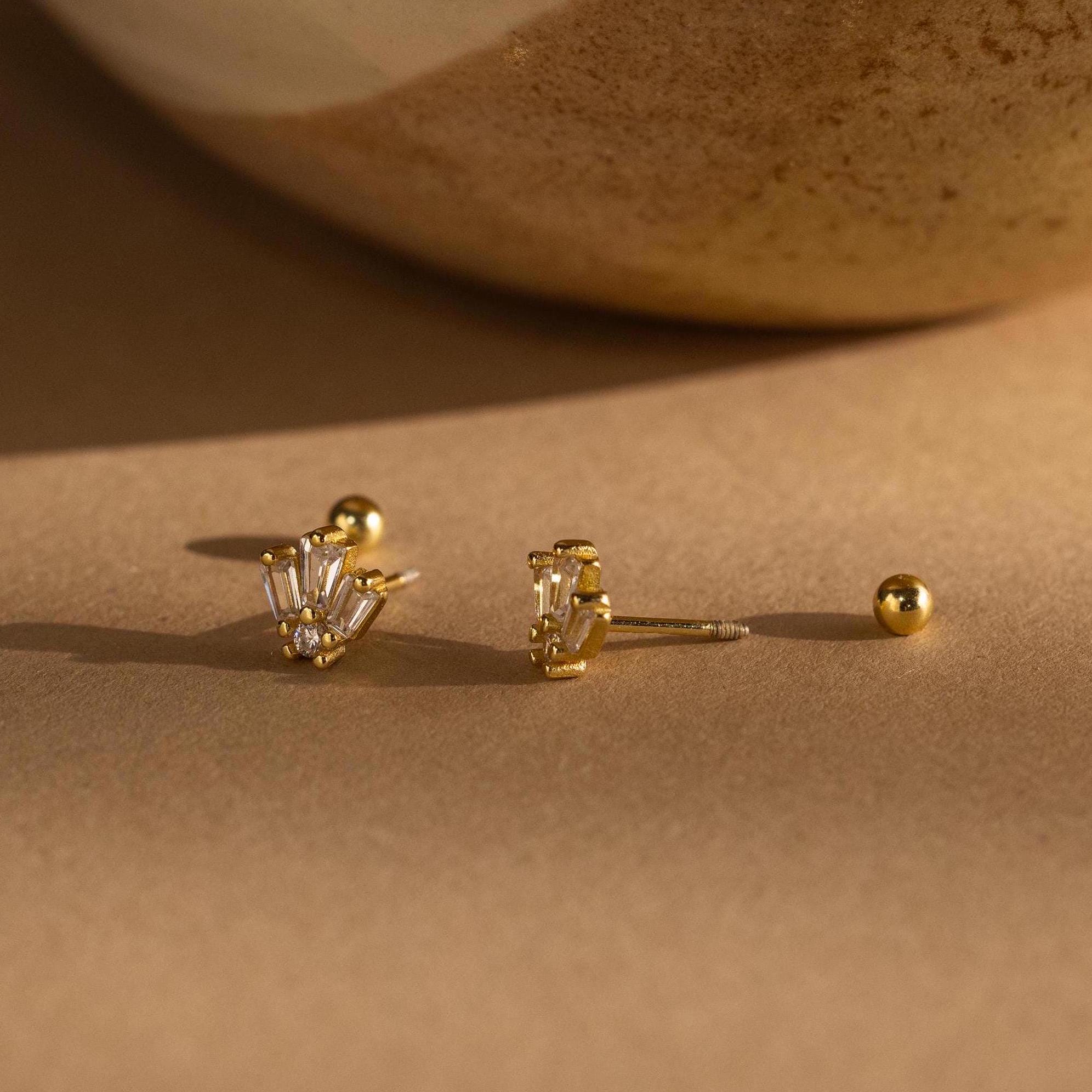 Art Deco Studs with baguette-cut clear stones bring vintage glamour, shown on a beige surface beside a ceramic accent.