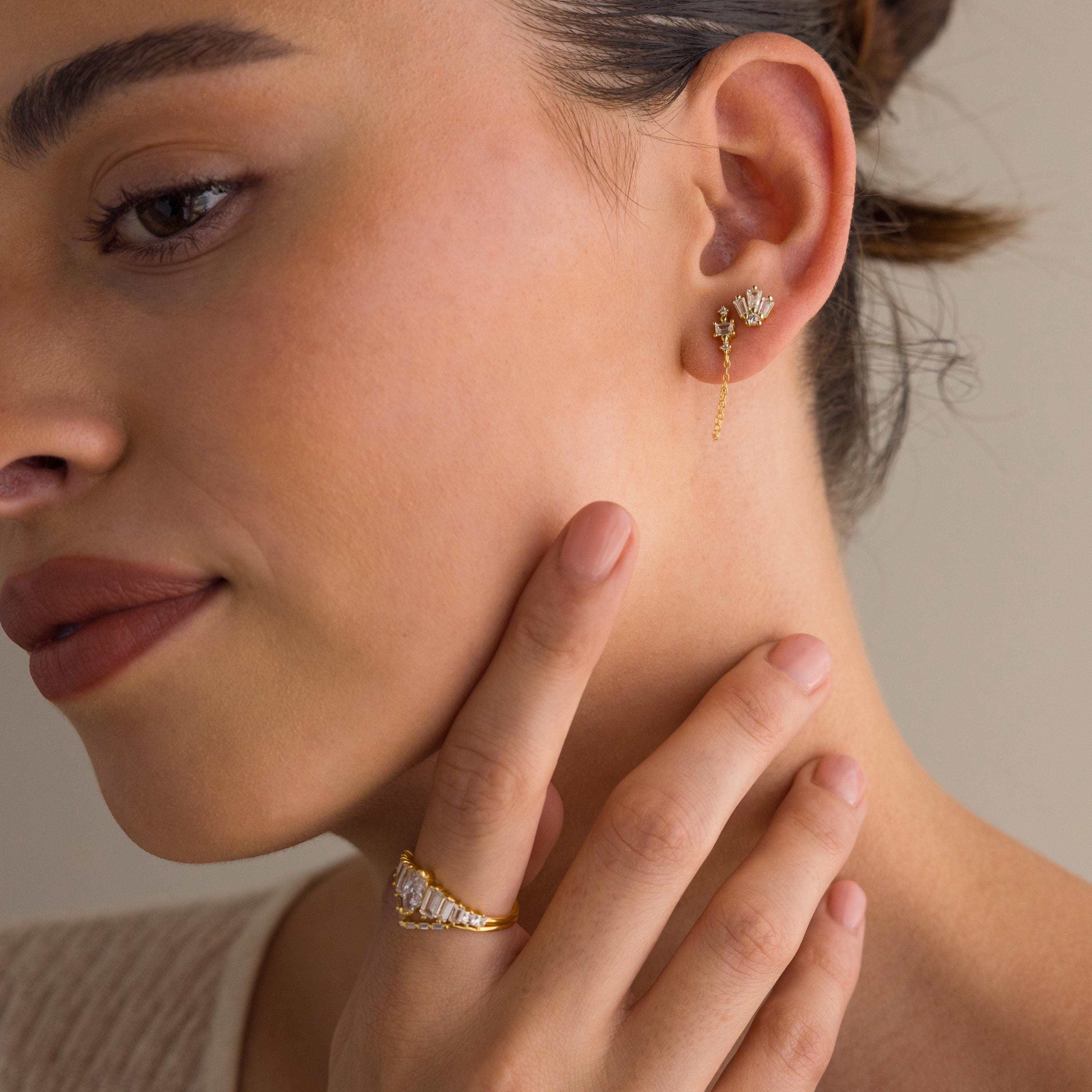 Woman wearing Art Deco Studs, exuding vintage glamour as she gently touches her face.