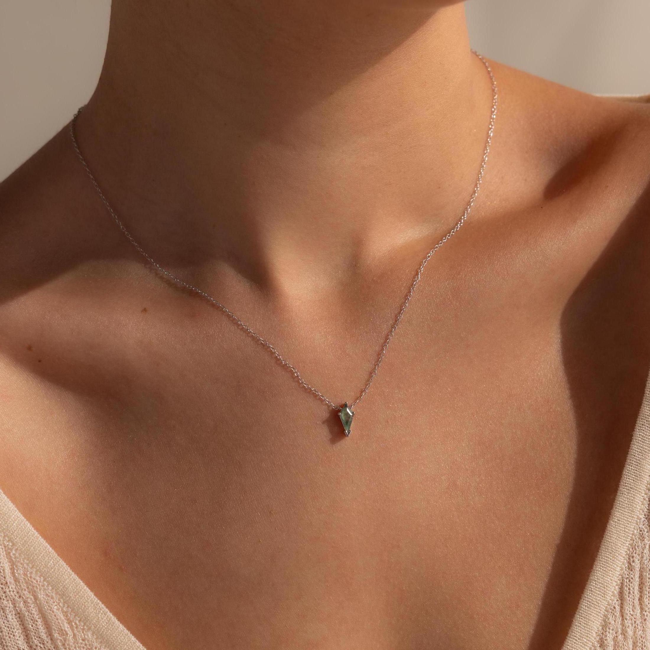 A close-up of a woman wearing the Agate Art Deco Pendant Necklace, featuring a delicate silver chain and a small geometric pendant.