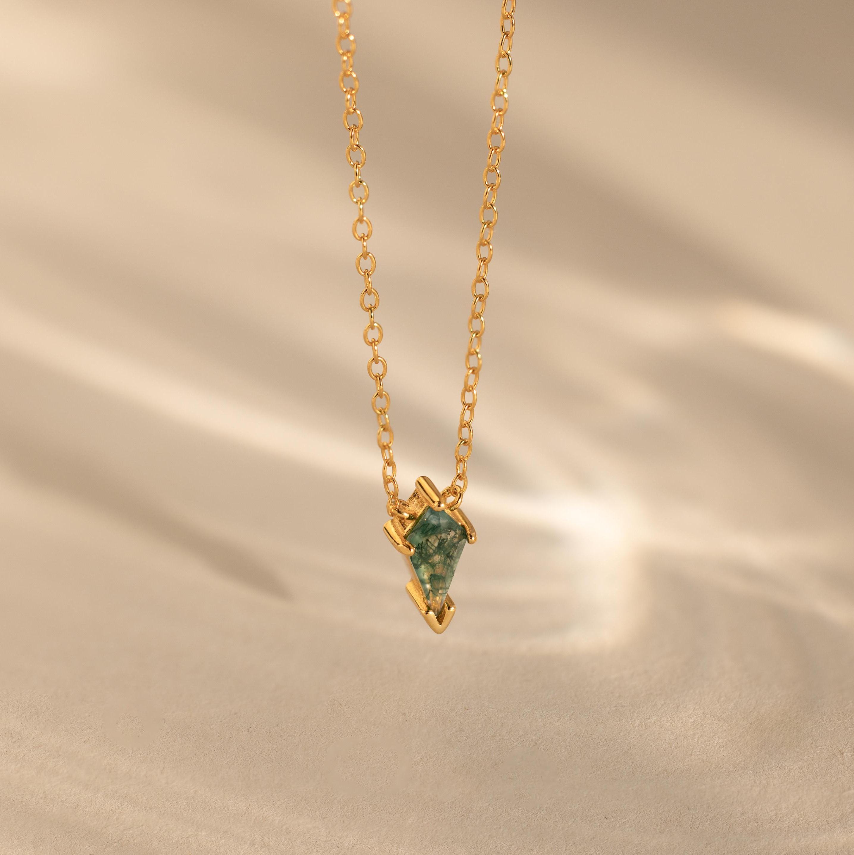 The Agate Art Deco Pendant Necklace features a gold chain and a green geometric moss agate pendant, displayed on a soft beige background for timeless elegance.