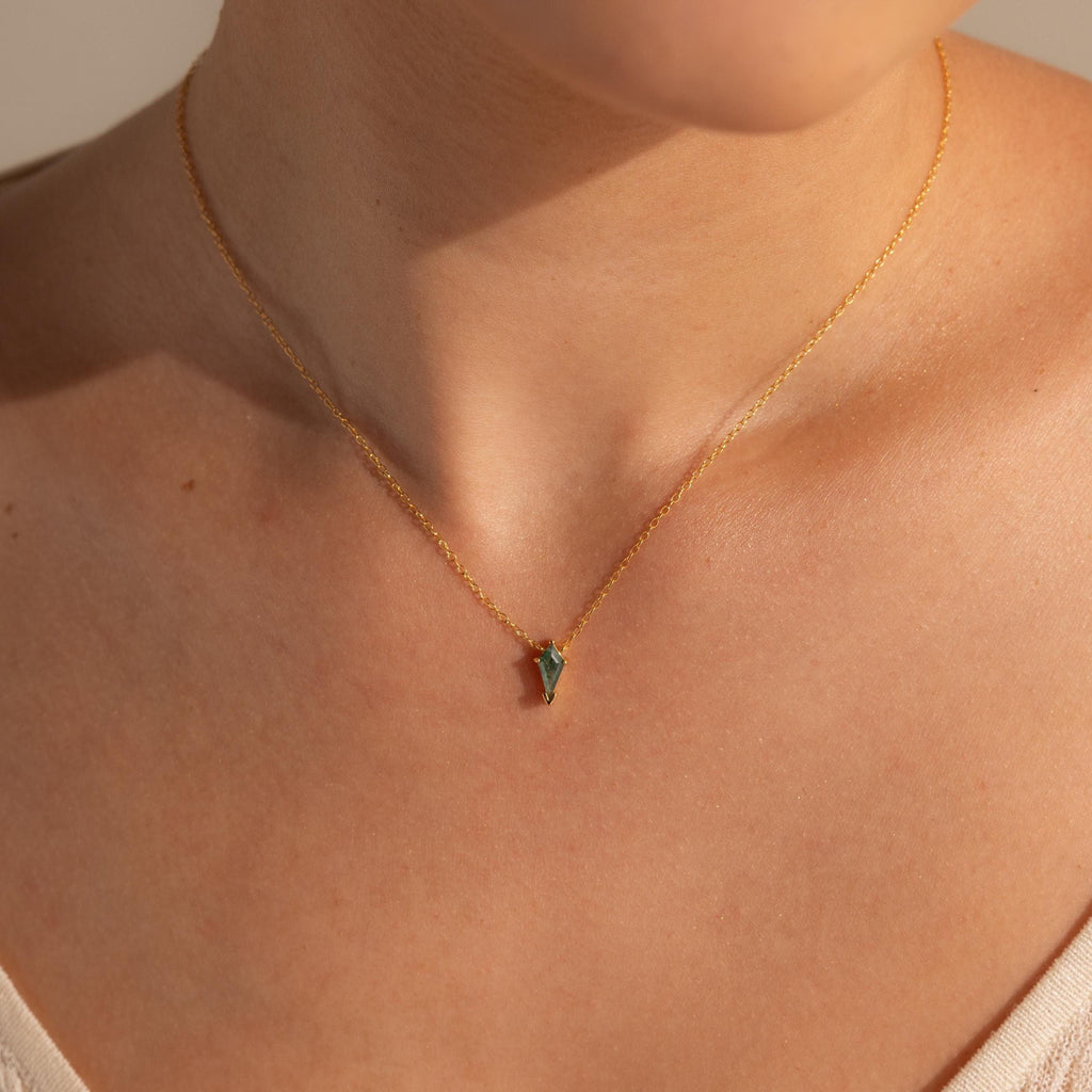 Close-up of a person wearing the Agate Art Deco Pendant Necklace, showcasing a thin gold chain with a small green moss agate pendant resting elegantly against bare skin.