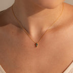 Close-up of a person wearing the Agate Art Deco Pendant Necklace, showcasing a thin gold chain with a small green moss agate pendant resting elegantly against bare skin.