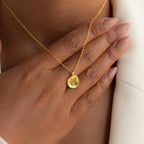 A hand with nude nails rests on the chest, showcasing the Pet Portrait Coin Necklace, a gold piece engraved with a lion—ideal custom jewelry for pet lovers.