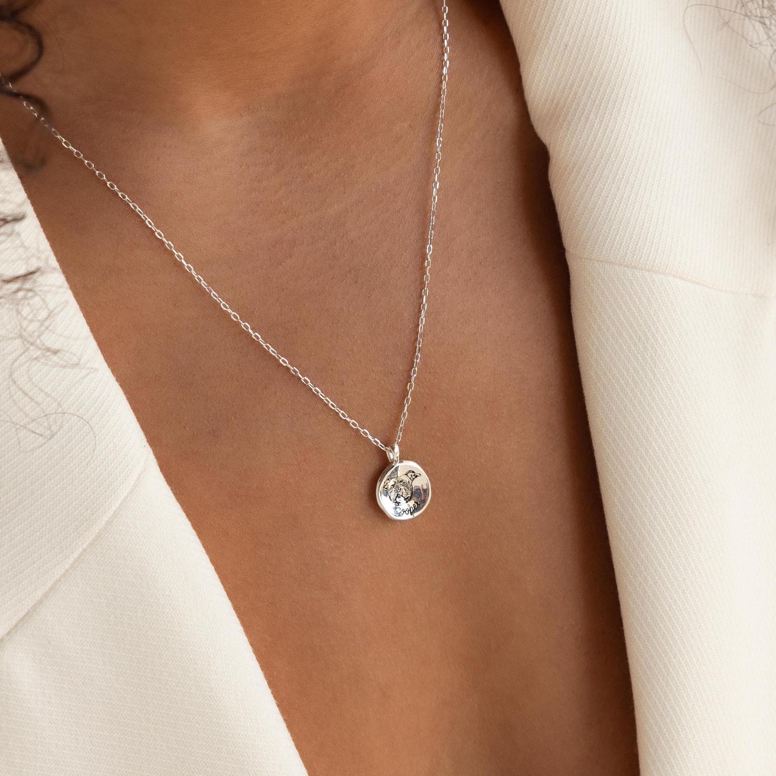 A woman wearing the Pet Portrait Coin Necklace, a silver pendant, paired with a cream-colored blazer.