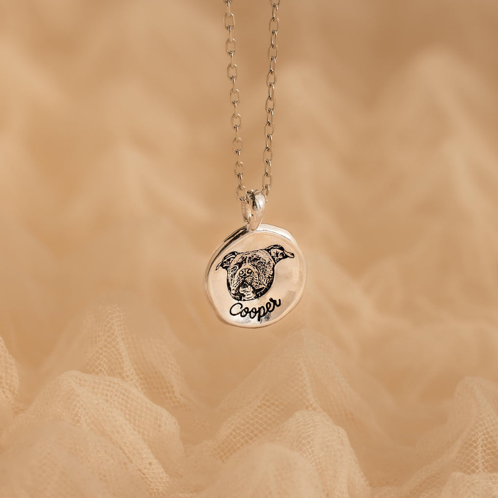 The Pet Portrait Coin Necklace is a silver custom piece featuring a round pendant engraved with a dog’s face and the name Cooper, perfect as pet memorial jewelry.