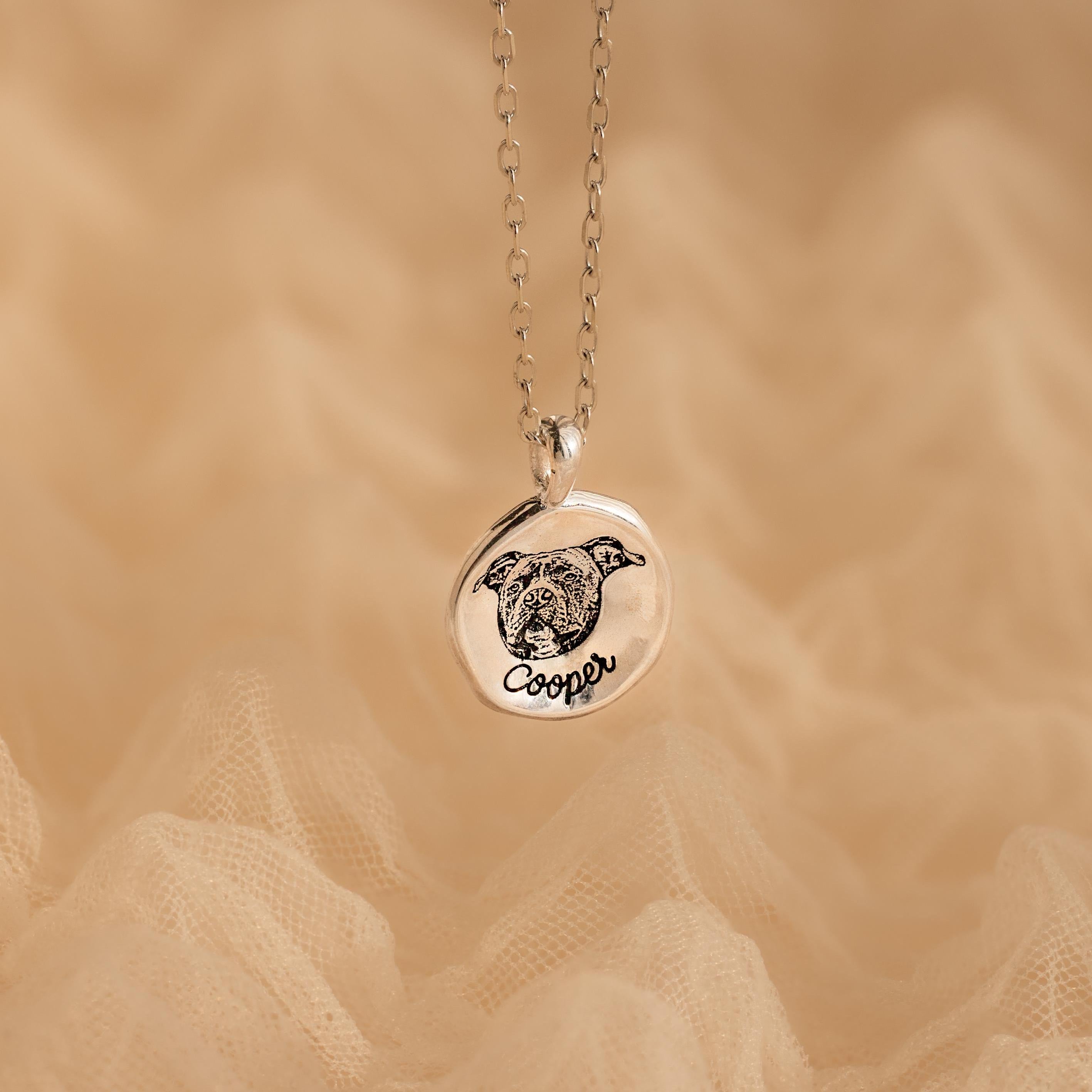 The Pet Portrait Coin Necklace is a silver custom piece featuring a round pendant engraved with a dog’s face and the name Cooper, perfect as pet memorial jewelry.