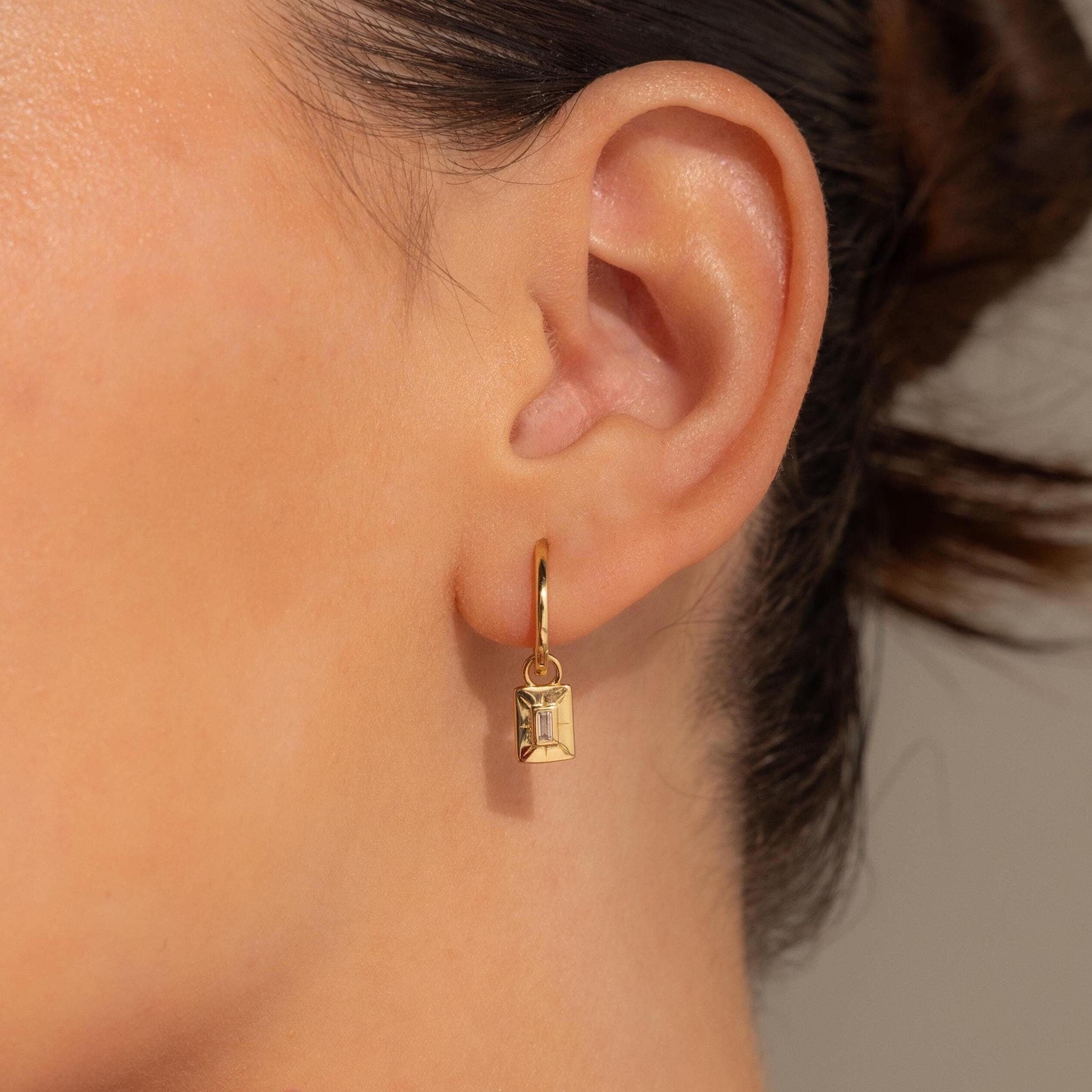 A close-up of a woman's ear adorned with Art Deco Diamond Tag Huggies, showcasing their vintage-inspired and timeless elegance.
