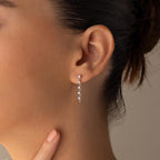 Woman wearing Diamond Chain Drop Earrings, touching her neck with one finger—these sparkling dangle earrings make a beautiful gift for her.