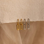 Two pairs of Pave Link Drop Earrings, one in gold and one in silver, rest on a textured beige surface. Each pair sparkles with elegant CZ Diamonds, capturing the classic beauty of rectangular hoop pave link drop earrings.