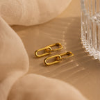 Pave Link Drop Earrings are displayed on a beige fabric background beside a clear glass dish.