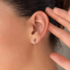 Close-up of a woman's ear wearing the Agate Kite Drop Earrings, featuring a small silver geometric design, with her hand near her ear.