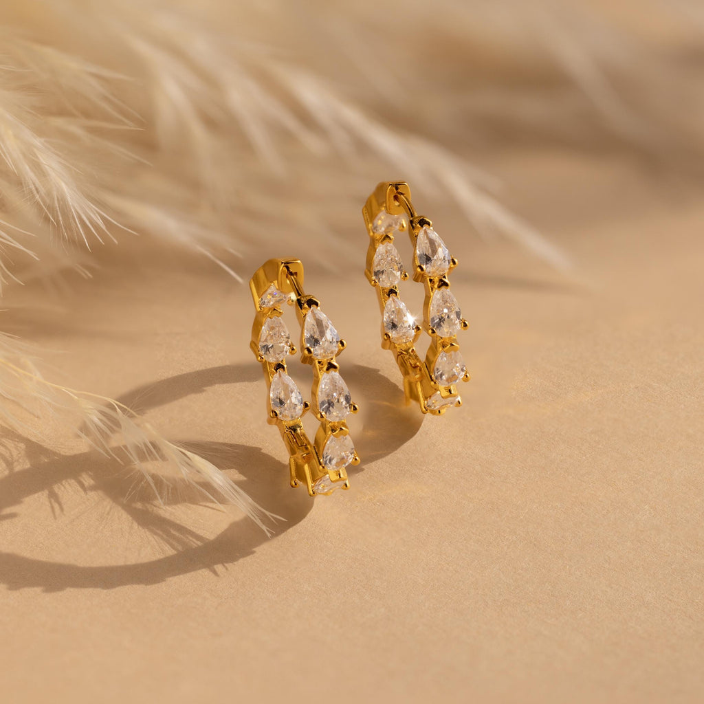 Inside Out Pear Diamond Hoops displayed on a beige surface with feathery accents—ideal as a bridesmaid gift or for anyone seeking statement diamond hoop earrings.