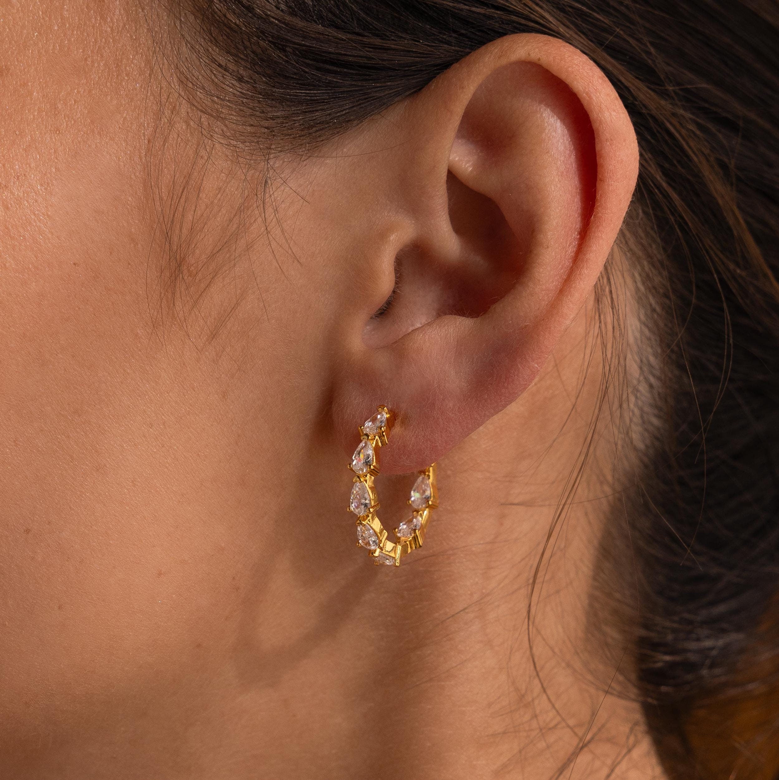 Close-up of a woman's ear wearing Inside Out Pear Diamond Hoops, featuring clear, teardrop-shaped stones—an elegant choice for a bridesmaid gift.