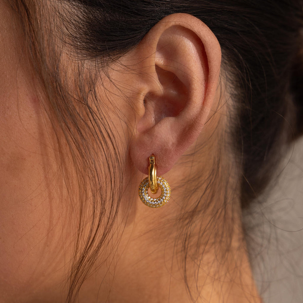 Close-up of a woman's ear wearing Duo Pave Link Hoops, bold earrings featuring shimmering gold and cubic zirconia accents.