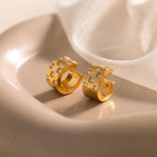 Pave Checkered Huggies gold hoop earrings with square patterns and sparkling gems, elegantly showcased on a beige ceramic dish.