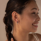 Woman with a braided hairstyle smiling, showing off her Link Drop Studs—elegant silver chain link earrings that add a touch of sophistication to her look.