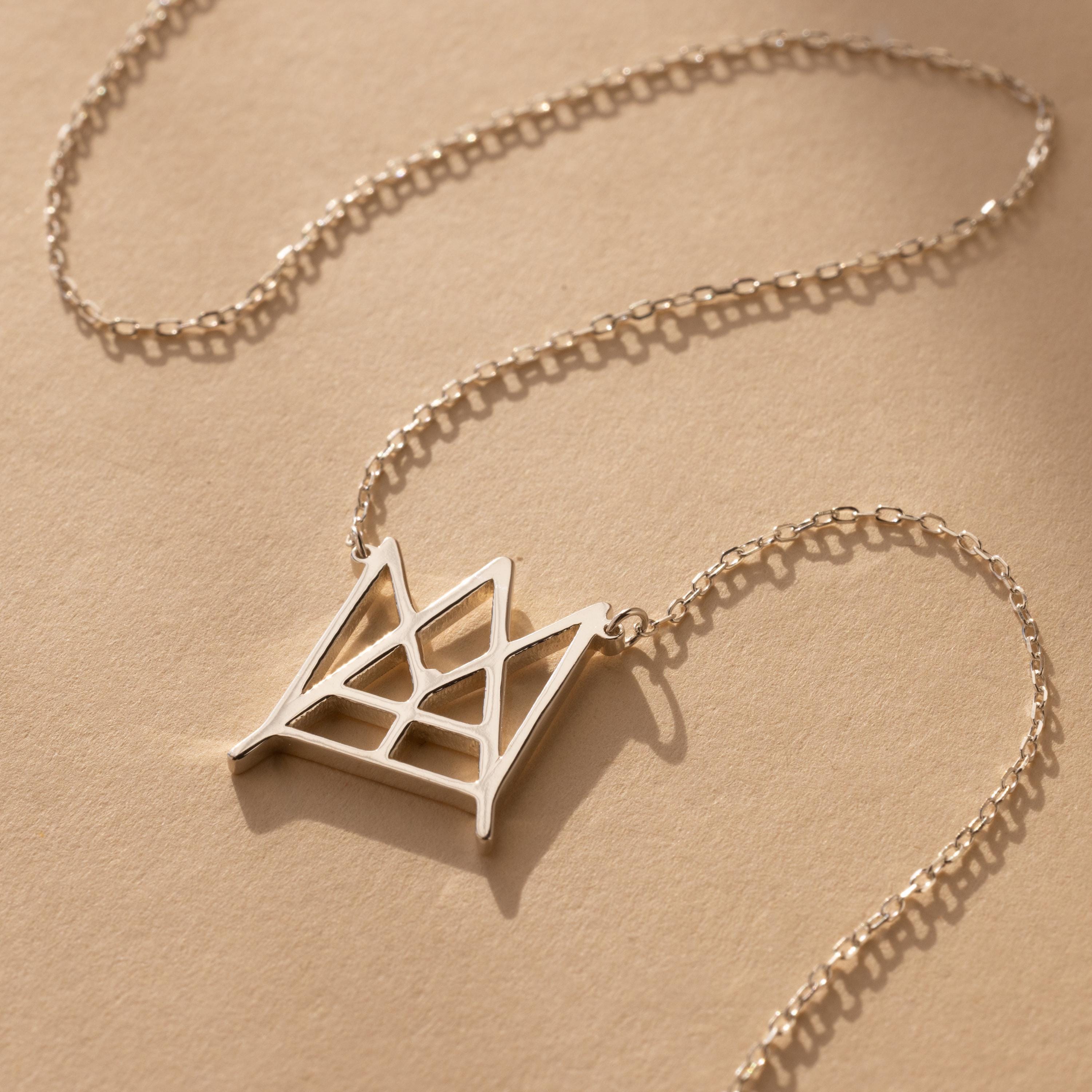 Modern Name Monogram Necklace featuring a gold chain and geometric crown-shaped pendant, ideal for those seeking personalized jewelry and contemporary necklace designs.
