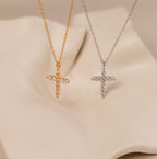 The Pave Cross Necklace, available in gold and silver with sparkling crystals, is displayed on a soft beige background—an ideal choice for those who love elegant jewelry.