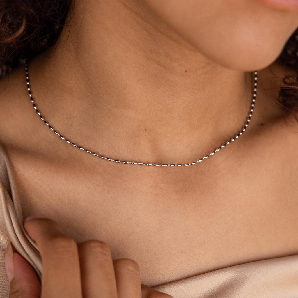 A woman in a beige top wears the delicate Oval Beaded Necklace.