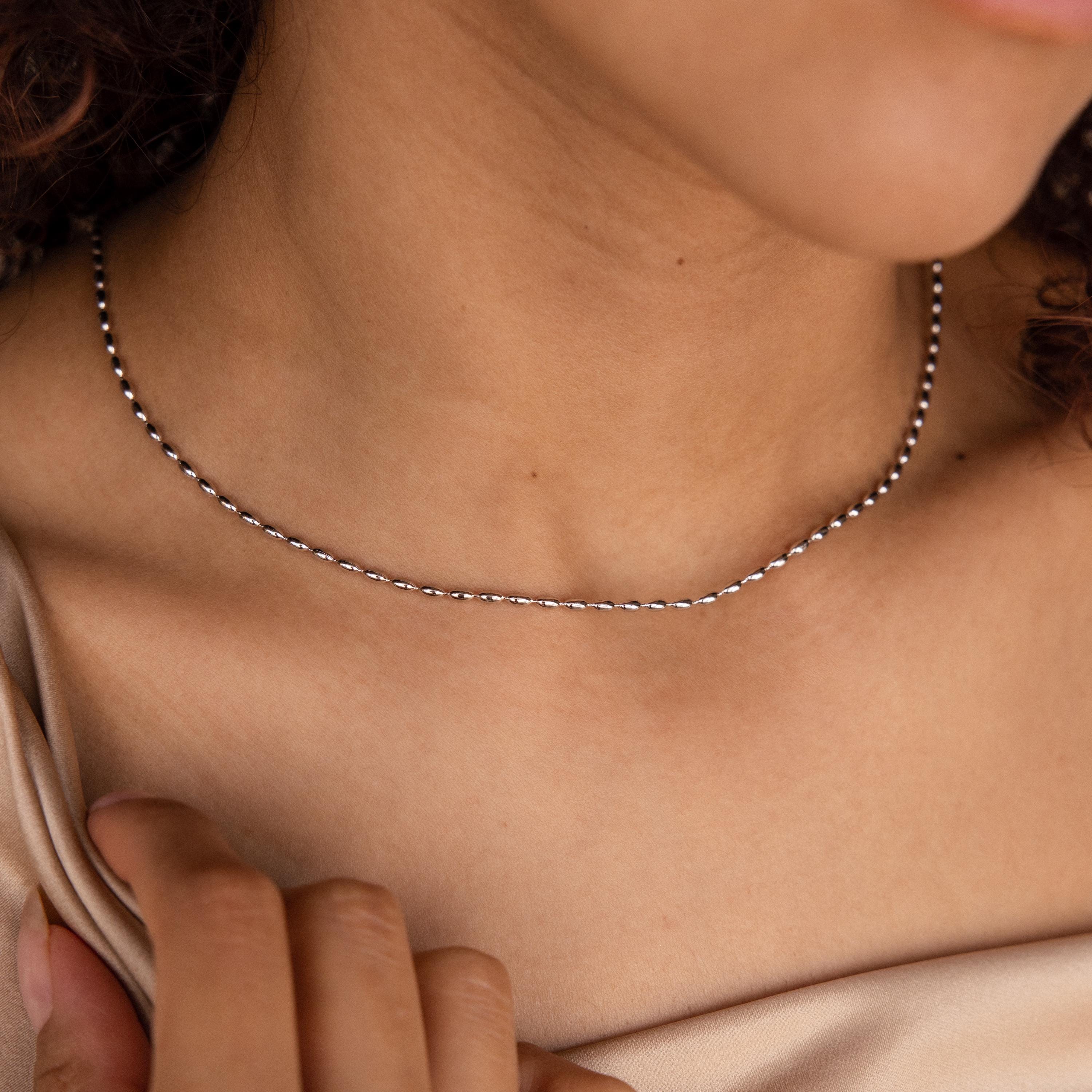 A woman in a beige top wears the delicate Oval Beaded Necklace.