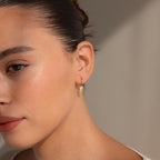 Close-up of a woman wearing Art Deco Diamond Tag Huggies, softly lit to highlight her features.