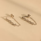 Diamond Chain Drop Earrings featuring silver chains and delicate accents, displayed on a beige surface—an elegant gift for her.