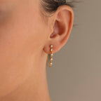 Close-up of a woman's ear wearing Diamond Chain Drop Earrings—delicate gold dangles with sparkling gemstones, an elegant gift for her.