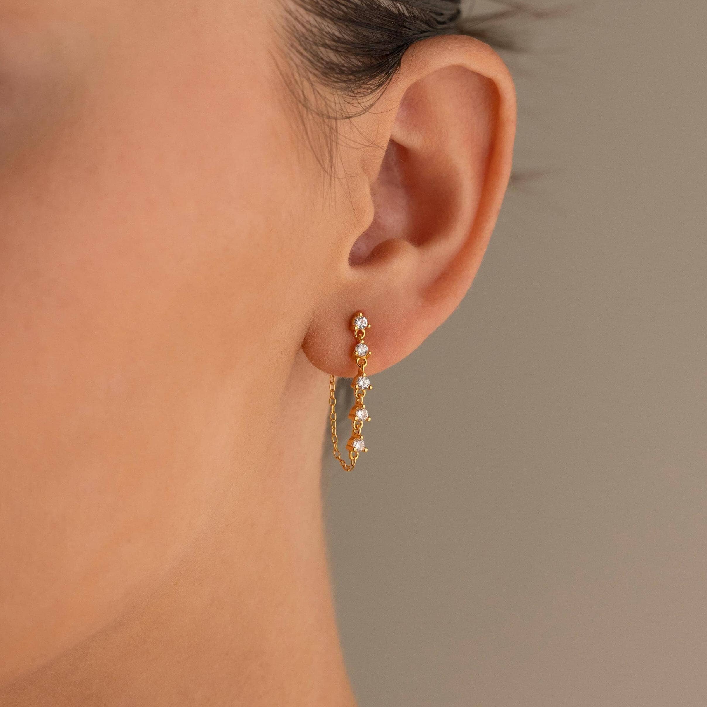 Close-up of a woman's ear wearing Diamond Chain Drop Earrings—delicate gold dangles with sparkling gemstones, an elegant gift for her.