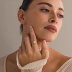A woman with natural makeup touches her face, showcasing the Vintage Diamond Rings Set with a cushion-cut halo and marquise-detailed band on her finger.