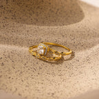 The Vintage Diamond Rings Set features cushion-cut halo stones and marquise-detailed bands, elegantly displayed on a textured beige surface.