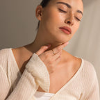 A woman in a cream sweater with eyes closed gently touches her neck, showcasing the Marquise Diamond Ring.