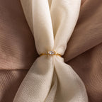 The Marquise Diamond Ring, featuring a gold finish band, is displayed on textured cream-colored fabric.
