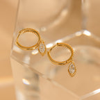 Marquise Pave Drop Huggies: Elegant gold hoop earrings feature marquise-cut crystal pendants, capturing the grace of marquise drop huggies and shimmering beautifully on a clear, faceted surface.