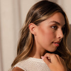 A woman wearing Pearl Ivy Flower Studs looks away from the camera.